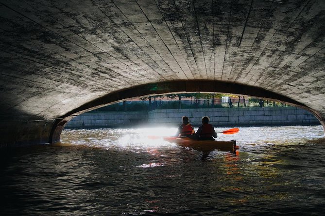 couple in a kayak on the river under the bridge